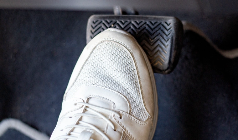 Right foot in a white shoe on the accelerator of a vehicle.